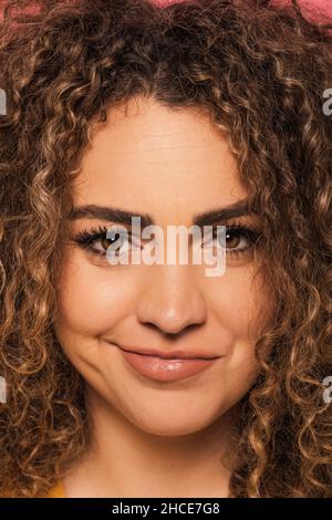Gros plan portrait d'une jeune femme aux cheveux bouclés regardant l'appareil photo en studio Banque D'Images