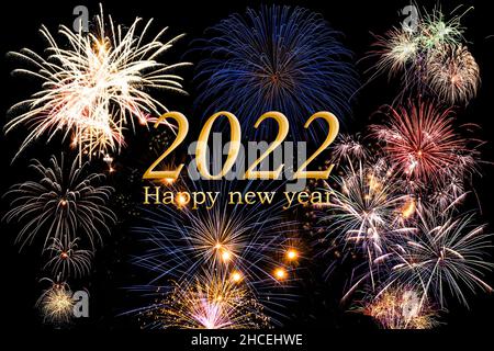 Bonne année 2022. Texte et chiffre en couleur dorée avec feux d'artifice lumineux, ciel sombre en arrière-plan. Banque D'Images