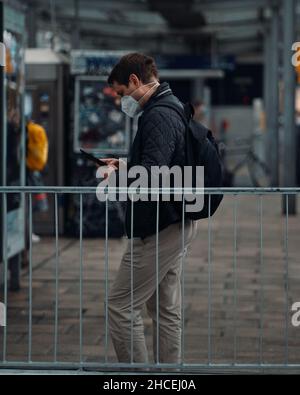 Plan vertical de l'homme avec un masque de visage debout sur la rue et la vérification de son téléphone. Banque D'Images