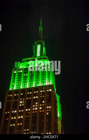 Vue à angle bas de l'Empire State Building éclairée par une lumière verte le jour de la Saint Patrick à New York. Banque D'Images