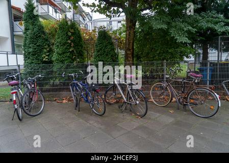 Vue de jour de quatre bicyclettes garées sur un trottoir près d'une cour privée Banque D'Images