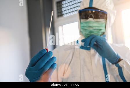 Technologue en santé médicale tenant le kit de prélèvement d'écouvillons COVID-19, portant des gants de protection PPE blancs, tube à essai pour la prise de patient OP NP Banque D'Images