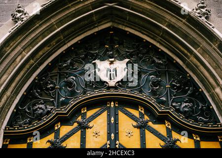 Porte voûtée avec éléments de décoration en fer forgé et armoiries avec un ange dans un ancien bâtiment Banque D'Images