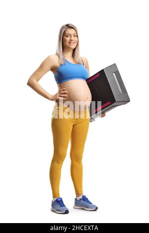 Portrait complet d'une femme enceinte dans des vêtements de sport tenant une plate-forme aérobie STEP isolée sur fond blanc Banque D'Images