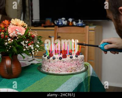 éclairant des bougies sur un gâteau d'anniversaire à la fête Banque D'Images
