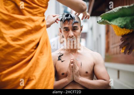 L'image rapprochée d'un bel homme asiatique se rase les cheveux par la tête de l'homme qui est ordonné dans le bouddhisme. Banque D'Images