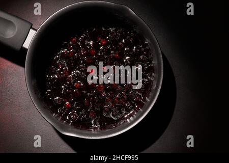 Confiture de framboises et de myrtilles dans un pot sur fond sombre.Faire de la confiture à la maison.Réserve maison. Banque D'Images