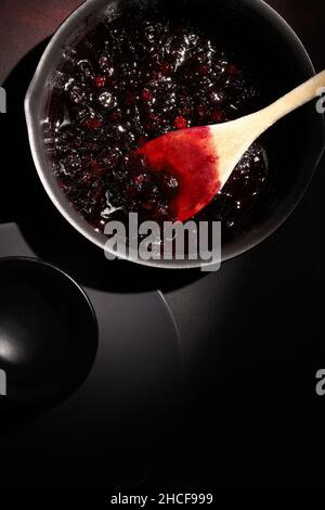 Confiture de framboises et de myrtilles dans un pot sur fond sombre.Faire de la confiture à la maison.Réserve maison. Banque D'Images