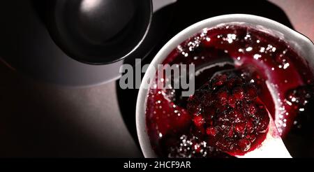 Confiture de framboises et de myrtilles dans un pot sur fond sombre.Faire de la confiture à la maison.Réserve maison. Banque D'Images