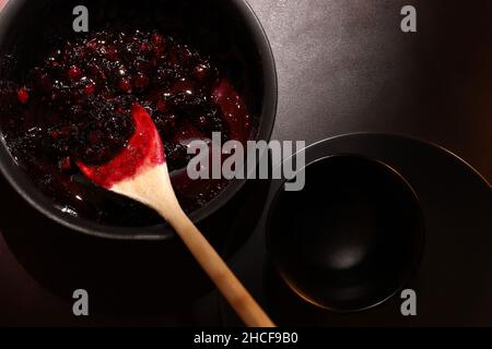 Confiture de framboises et de myrtilles dans un pot sur fond sombre.Faire de la confiture à la maison.Réserve maison. Banque D'Images