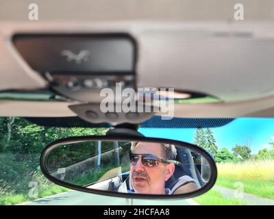 Vue arrière du conducteur mâle regardant le rétroviseur intérieur de la voiture Banque D'Images