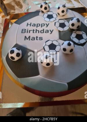 Gâteau d'anniversaire sportif amusant et charmant. Design avec le terrain de football. Chaussures, bâtiments, journée sportive. Gâteau, crème. Champ vert. Gâteau d'anniversaire pour un sport Banque D'Images