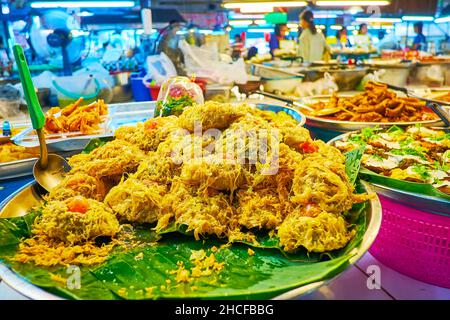 Le bol avec des morceaux de poisson frits dans l'oeuf sur les feuilles de banane verte, marché de Tanin, Chiang Mai, Thaïlande Banque D'Images