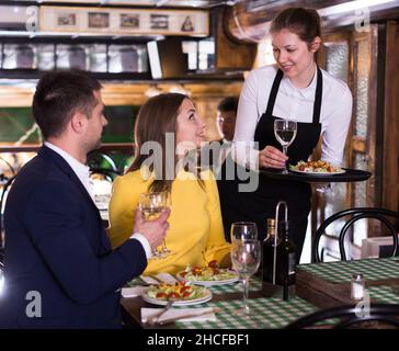 Femme serveur apporte ordre à couple qui ont le dîner et boire du vin Banque D'Images