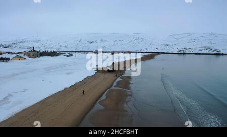 Vue aérienne des vieux navires rouillés laissés sur la rive sablonneuse près de la rive océanique en hiver.Survolant les personnes qui marchent sur la plage près de l'Ocea froid Banque D'Images