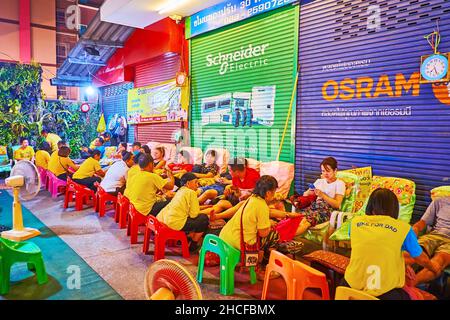 CHIANG MAI, THAÏLANDE - 4 MAI 2019: Le salon de massage thaïlandais en plein air, vu derrière les guirlandes éclairées dans le marché de samedi soir, rue piétonne Wualai Banque D'Images