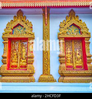 Le mur latéral du Viharn avec pilier en bois sculpté doré et fenêtres avec volets et cadres, décoré de motifs et sculptures dans le style Lanna Banque D'Images