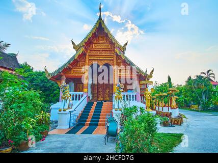 La façade du pittoresque viharn historique de Wat Puak Hom avec toit en pignon (pyque), sculptures de lion Singha, serpents Naga sur bargeboards et patt doré Banque D'Images