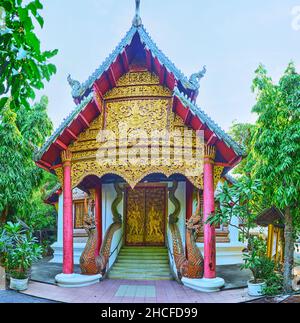 La façade en bois sculpté du Viharn avec des piliers, des sculptures, des motifs dorés, une représentation de Kinnara sur les portes et des sculptures de serpents Naga, Wat Puak Taem t Banque D'Images