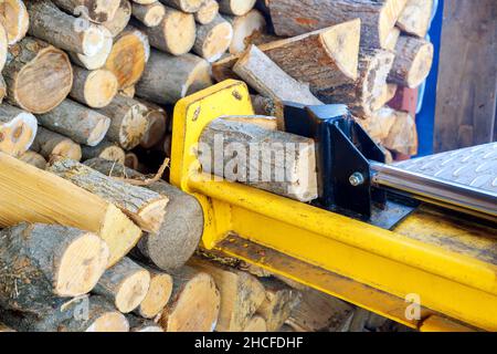 Un homme travaillant avec le bois de chauffage pour diviser les bûches par la machine Banque D'Images