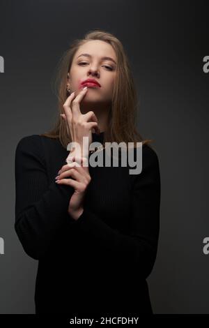 Jeune femme avec un maquillage tassé dans la robe noire et la chaîne d'or Banque D'Images