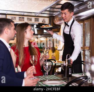 Homme serveur est apporte ordre à couple qui ont le dîner et boire du vin Banque D'Images