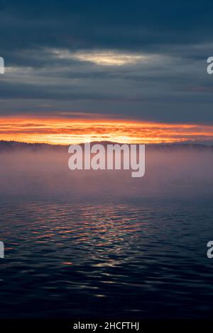 Vue spectaculaire sur le coucher du soleil à travers le brouillard au-dessus de la mer Banque D'Images