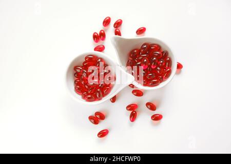 Huile de krill capsules de gélatine rouge dans les tasses blanches ensemble .acides gras oméga.alimentation saine et suppléments alimentaires Banque D'Images