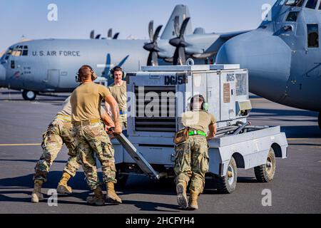 Les aviateurs affectés à l'unité de maintenance des aéronefs expéditionnaires de 61st, poussent une alimentation externe avant d'effectuer la maintenance d'un C-130J Super Hercules affecté à l'escadron de transport aérien expéditionnaire de 61st à la base aérienne Ali Al Salem, au Koweït, le 22 novembre 2021.L’ASAB est connu sous le nom de Theatre Gateway du Commandement central des États-Unis et est capable de répondre aux imprévus par des opérations de transport aérien tactique.(É.-U.Photo de courtoisie de la Force aérienne par 1st Lt Nathan Lowe) Banque D'Images