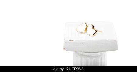 Puces d'oreilles en forme de coeur dorées sur fond blanc. Banque D'Images