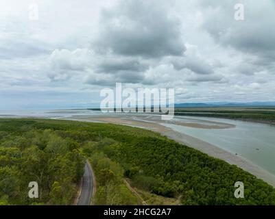 Route sinueuse dans le Bush à côté d'un ruisseau marécageux sous un ciel orageux à Conway Beach Queensland Australie Banque D'Images