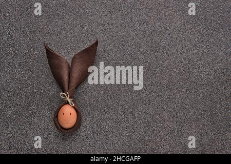 Concept de cadeau de Pâques - œuf emballé en forme de lapin sur fond de pierre sombre Banque D'Images