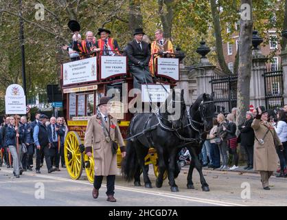 Des membres de la Compagnie Wheelwrights, dans des robes de livrée traditionnelles, à cheval sur un bus omnibus de 1911 tiré par le Lord Mayor’s Show 2021, Londres. Banque D'Images