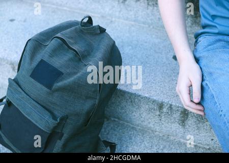 sac à dos posé sur les escaliers avec la main d'un jeune homme à côté Banque D'Images