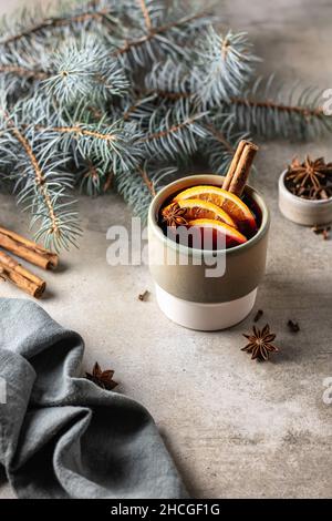 Traditionnel Noël boisson chaude de vacances vigne avec des épices, des tranches d'orange en verre céramique avec branche de l'arbre de Noël et des épices autour sur texture Banque D'Images