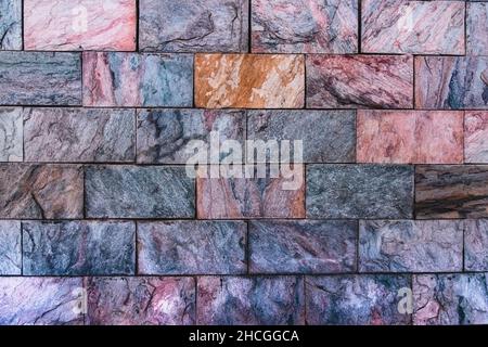 Revêtement mural décoratif avec carreaux de granit multicolores. Arrière-plan de pierres naturelles colorées. Revêtement décoratif avec ston naturel multicolore Banque D'Images