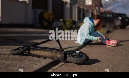 Une femme de race blanche est tombée d'un scooter électrique et a blessé sa jambe.Souffrant de douleur. Banque D'Images