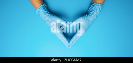 Médecin mains dans des gants montrant un masque médical sur fond bleu.Mesures préventives pour protéger contre l'infection par le virus Covid-19 Corona. Banque D'Images