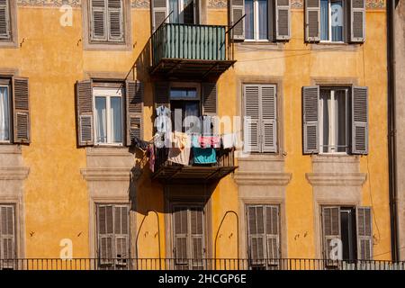 Ancien bâtiment méditerranéen antique d'oranger, façade avec fenêtres en bois et volets.Linge suspendu d'un balcon. Banque D'Images