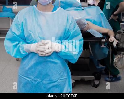 Accent sélectif sur le chirurgien dans les gants en uniforme et en latex dans la salle d'opération.Le médecin de la salle d'opération se tient avec ses doigts clastés dans des gants stériles. Banque D'Images