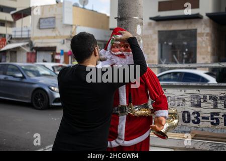 Un commerçant met la tête sur une poupée du Père Noël à Jaffa, tel Aviv, Israël Banque D'Images