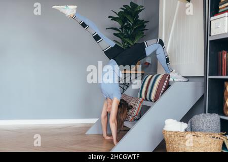 Femme de forme physique faisant l'exercice d'étirement de dos à la maison, l'entraînement, la main et une posture de roue à une jambe Banque D'Images