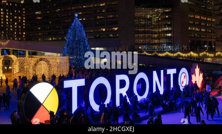 People by the Toronto 3D sign situé dans Nathan Phillips Square.Le grand arbre de Noël et d'autres lumières sont vus en arrière-plan.29 décembre 2021 Banque D'Images