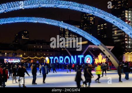 Les personnes qui patinent sous les « Arches de la paix » dans Nathan Phillips Square, qui sont décorées avec des lumières de Noël.29 décembre 2021 Banque D'Images