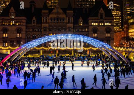 Les personnes qui patinent sous les « Arches de la paix » dans Nathan Phillips Square, qui sont décorées avec des lumières de Noël.29 décembre 2021 Banque D'Images