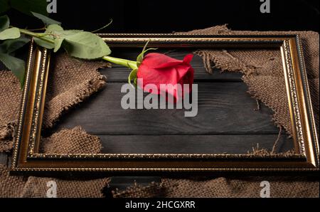 Dans un beau cadre, des pièces de toile et une rose rouge sur un fond en bois. Banque D'Images