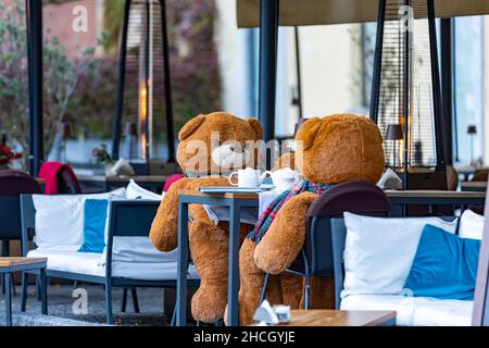 Deux ours en peluche buvant du thé assis à une table de bar sur la place italienne Banque D'Images