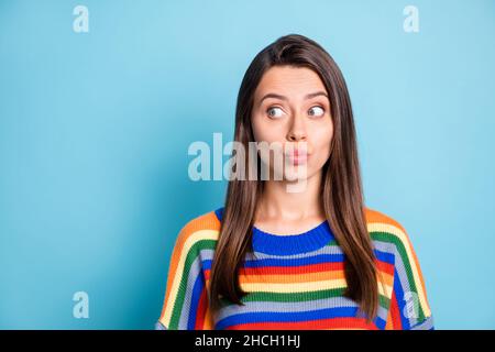 Photo portrait de jolie fille mignonne envoi air baiser lèvres pouted regardant l'espace vide curieux isolé sur fond bleu vif de couleur Banque D'Images