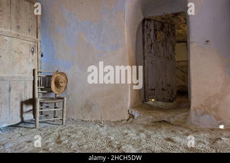 Encore la vie avec chaise en bois et chapeau de paille, chambre d'une maison de grotte, Andalousie, Espagne Banque D'Images