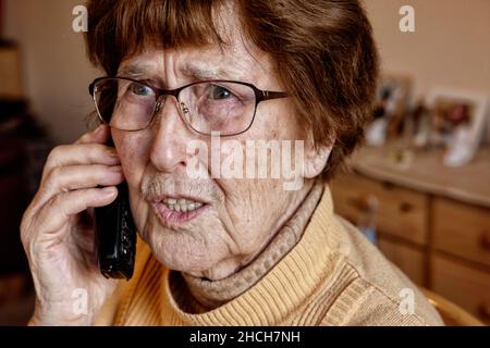 Senior à la maison tandis que le téléphone semble incertain, petit-fils tour, Cologne, Rhénanie-du-Nord-Westphalie, Allemagne Banque D'Images